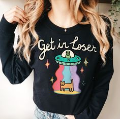 Alien Love UFO Sweatshirt, Retro UFO Jumper, Harajuku Groovy Space Sweater, Positive Quote Crewneck, Trendy Planets School Sweatshirt UNISEX Who can resist this aesthetic Space UFO Sweatshirt? It's comfy and soft make makes a perfect gift for a loved one, or for anyone who is a fan of the extraterrestrial or space. The quote on the jumper reads 'Get in loser'. The cute jumper and available in multiple colours and sizes. *MADE TO ORDER ITEM*   - - FEATURES - - - 50% cotton, 50% polyester - Medium Retro Long Sleeve Top With Funny Print, Retro Winter Tops With Cartoon Print, Retro Tops With Funny Print For Fall, Fun Long Sleeve Slogan Tops, Space Sweater, Alien Love, Cute Jumpers, School Sweatshirts, Aesthetic Space