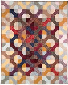 a multicolored patchwork quilt with circles and squares on the front, in various colors