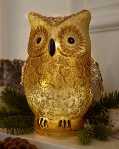 an owl figurine sitting on top of a mantle next to some pine cones