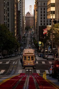 a trolley car is going down the street in front of some tall buildings and cars