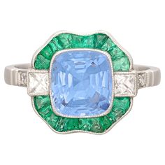 an art deco ring with a blue and green stone surrounded by white gold, diamonds and emeralds