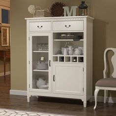 a white china cabinet with glass doors and shelves on the top, next to a chair