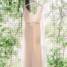 a wedding dress hanging on a rack in front of a window with ivy growing around it