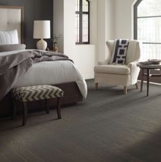 a bedroom with wood flooring and white bedding in the center, two chairs on either side