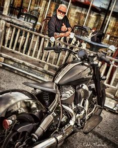 an older man sitting on a motorcycle in front of a restaurant with his arms crossed