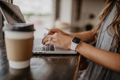 a woman sitting at a table with a laptop computer and cup of coffee in front of her