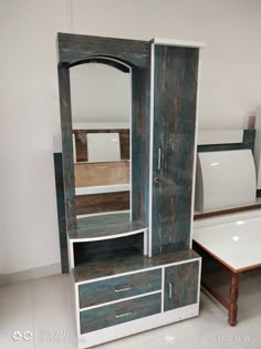 a wooden cabinet with drawers and mirror on the top, next to a white table