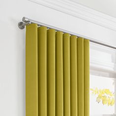 a yellow curtain hanging on the side of a white wall next to a windowsill