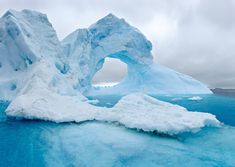 an iceberg in the ocean with blue water and snow on it's sides