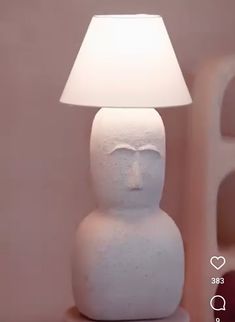 a white lamp sitting on top of a table next to a pink wall with hearts