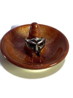 a small brown bowl with a ring on it's center and a white background