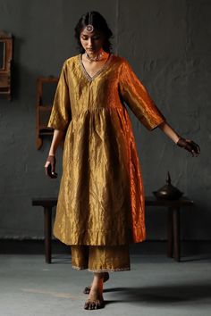 Elevate your style with exquisite tissue silk kurta and pant set, a perfect blend of traditional elegance and modern flair. Crafted from lightweight tissue silk, the kurta features a delicate sheen that catches the light with every movement, adding a touch of luxury to your ensemble. The kurta with intricate handwoven details that showcase the artistry and craftsmanship of Indian textiles. The graceful embroidery , adorns the neckline and cuffs, creating a captivating focal point. The relaxed silhouette and three-quarter sleeves ensure comfort without compromising on style. Paired with the kurta is a matching tissue silk pant that complements the ensemble beautifully. The pant features a comfortable elastic waistband and a flattering straight cut, offering a chic and versatile look. Whethe Shorshe Clothing, Tissue Suit, Silk Dress Plus Size, Gold Anarkali, V Neck Anarkali, Salwar Kurti, Desi Wardrobe, Haldi Outfits, Gold Suit