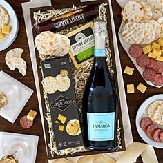 an assortment of cheeses, crackers, and wine in a gift box on a table