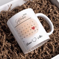 a white coffee mug with a calendar on it