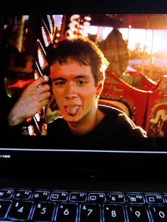 a man sticking his tongue out in front of a laptop screen with the image of himself on it