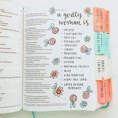 an open bible with flowers and words on the pages that read a godly woman's