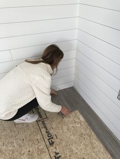 a woman kneeling down on the floor in front of a wall