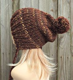 "Style: Chunky knit beanie with pom pom and braided ties, for men or women. Color: This sample hat is shown in Sequoia, a mix of browns, golds and rust. Sizes: One size fits average teen or adult head size of 20\" to 23\" (50.5 cm to 58 cm). Fiber Content: 80% acrylic, 20% Wool Characteristics: Chunky, very soft, warm and cozy. Care Instructions: Hand wash, dry flat. Every item from Pixiebell is handmade and knit or crocheted to order, unless otherwise stated in title of the item as \"ready to s Brown Knitted Beanie Cap, Knitted Brown Yarn Bonnet, Brown Yarn Bonnet Hat, Brown Knitted Beanie, Cozy Knitted Brown Bonnet, Cozy Brown Knitted Bonnet, Hand Knitted Brown Bonnet One Size, Brown Knitted Hats For Cold Weather, Knitted Brown Acrylic Yarn Hats