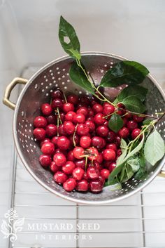 a metal colander filled with lots of cherries