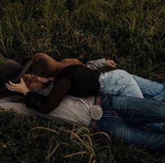 a woman laying on the ground with her head in her hands while wearing a cowboy hat