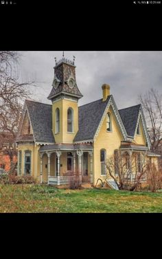 an old yellow house with a clock tower on the front and side of it's roof