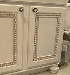 a white cabinet with beaded trim around the doors