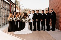 a group of people standing next to each other in front of a brick wall and building