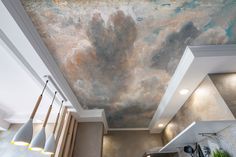 a painting on the ceiling of a kitchen with lights hanging from it's sides