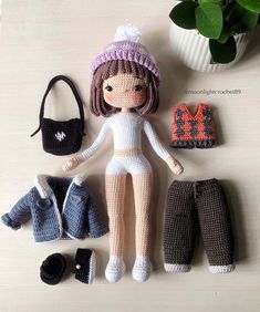 a crocheted doll is posed next to her purse and other items on the table