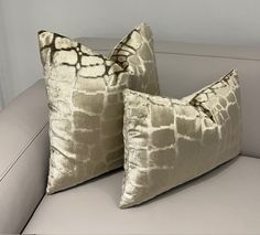 two pillows sitting on top of a white couch