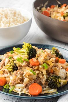 a plate with rice, carrots and broccoli next to a bowl of rice