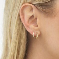 a close up of a person wearing gold earring with diamond hoops on their ears