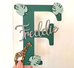 a person holding up a wooden sign with a giraffe and leaves on it