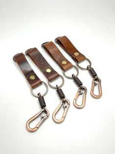 five leather keychains with metal hooks on them