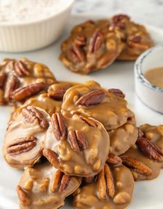 several pecan cookies on a plate next to a bowl of powdered maple syrup