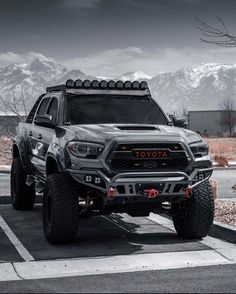 a large gray truck parked in a parking lot with mountains in the backgroud