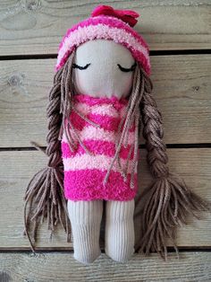 a stuffed doll with dreadlocks and a scarf on top of a wooden floor