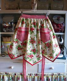 an apron hanging on a rack in front of a cabinet with dishes and utensils