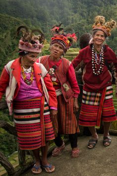 three women in colorful clothing standing on the side of a hill