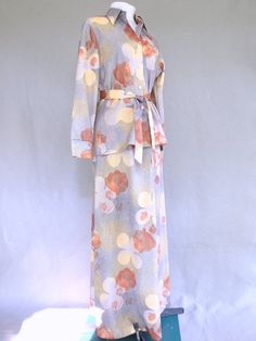 This vintage 1970's mod two piece dress has a fall colored floral pattern.  The polyester maxi outfit has a button shirt with a wide collar and long sleeves with 2 button cuffs.  The ankle length skirt has an elastic waist.An optional sash can be used as a belt or at the neck.Maker: Seaton HallContent tag:  none, but this is 100% polyesterSize tag: 16 - measures to fit a size 8, SmallCare tag:  machine wash and dryCondition:  ExcellentRed, white and blue ILGWU tag.The top is 25.5 inches (65 cm) Retro Long Sleeve Sets For Fall, Retro Long Sleeve Spring Set, Retro Spring Daywear Sets, Vintage Long Sleeve Daywear Sets, Vintage Long Sleeve Spring Sets, Vintage Long Sleeve Sets For Spring, Vintage Sets For Spring Daywear, Vintage Floral Print Sets For Spring, 2 Piece Dress