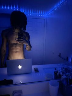 a man with no shirt on is looking at his laptop