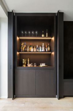 an open cabinet with bottles and glasses on it