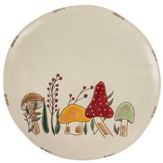 a plate with mushrooms and plants painted on the front, sitting on a white surface