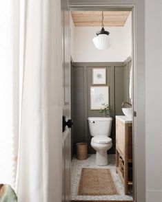 a white toilet sitting in a bathroom next to a wooden cabinet under a light fixture