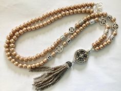 Lovely long latte glass pearl tassel necklace This necklace has been made using glass pearl beads, silver plated spacer beads, Tibetan silver beads,  Silver tone bead caps, Tibetan silver connecter  and long beaded tassel  The necklace measures 33" plus 1" connecter and 3" tassel, 37" overall A pretty satin pouch is available to keep your item safe Please follow the link If there is a particular piece you like but would prefer it in another colour, shortened or lengthened please contact me I can Long Beaded Necklace With Tassels As Gift, Elegant Beaded Long Tassel Necklace, Adjustable Beaded Long Tassel Necklace, Gold Beaded Dangle Tassel Necklace, Adjustable Long Metal Tassel Necklace, Satin Pouch, Flapper Necklace, Semi Precious Gems, Necklace Beaded