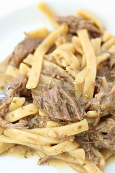 a white plate topped with pasta and meat