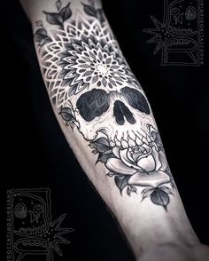 a black and white skull with flowers on it's arm