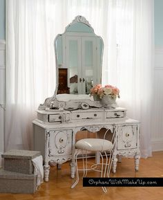 a white dressing table with a mirror and chair