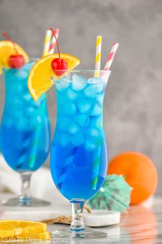 two blue lagoon cocktails with lemon slices and cherries