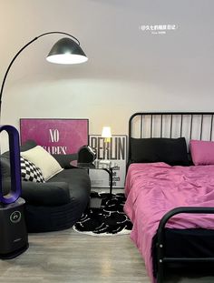 a bed room with a neatly made bed next to a black chair and a lamp